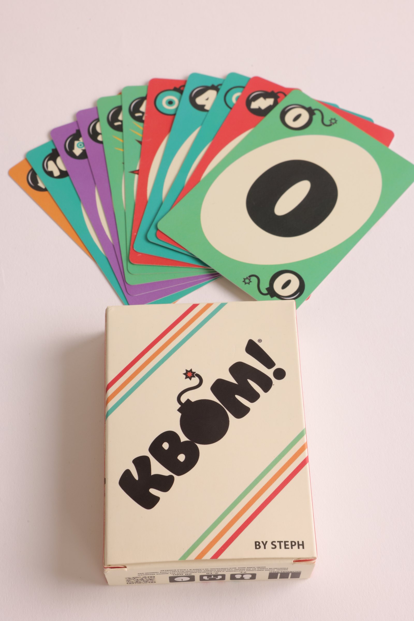 Cream KBÓM box with a fan of cards